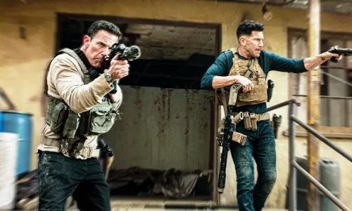 Cena de ação intensa em O Contador 2, com Christian Wolff e Brax armados em uma missão arriscada, mostrando o dinamismo do filme.